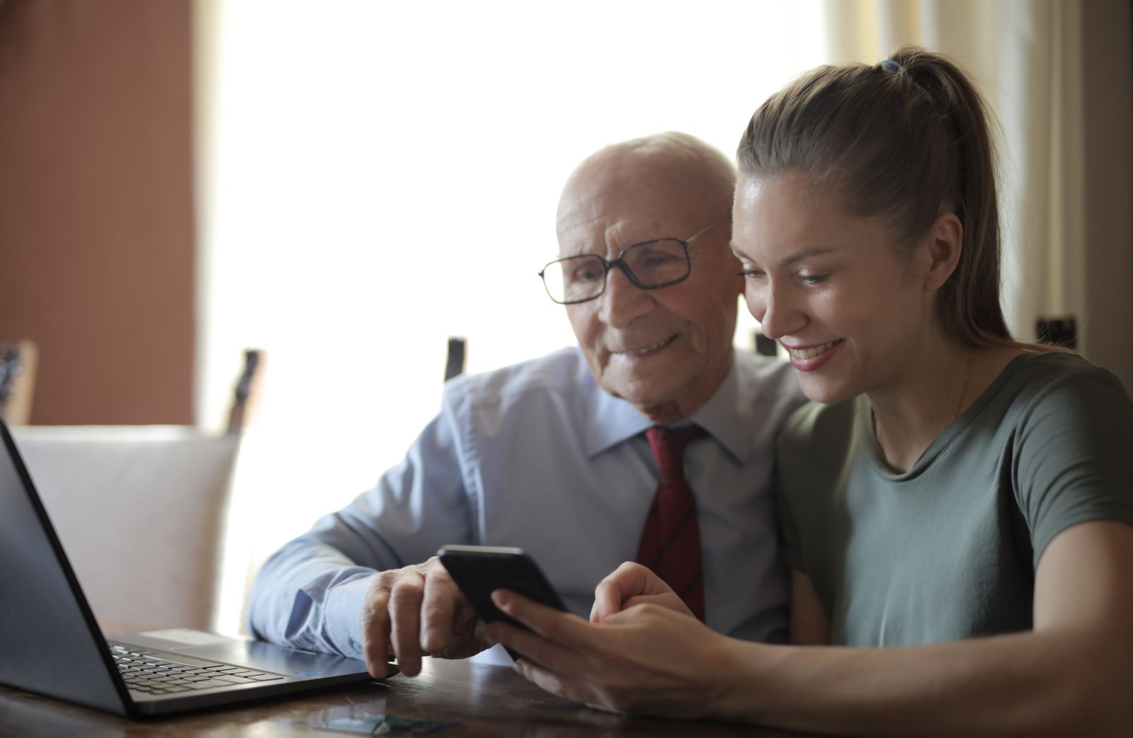 A young digital mentor and an older man looking at a smartphone together